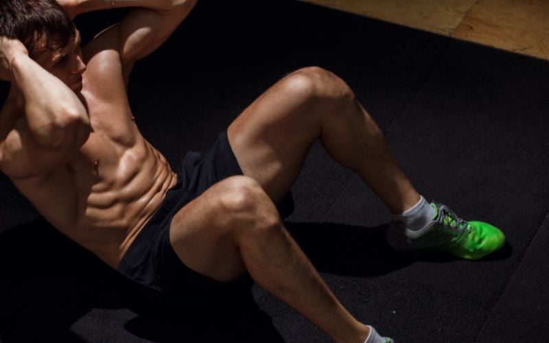 Ripped shirtless man doing ab crunches in the gym