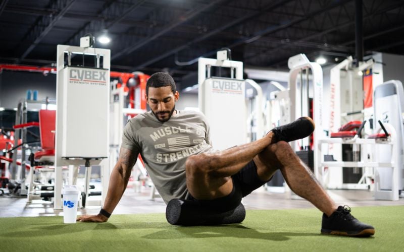 Male athlete foam rolling in the gym.