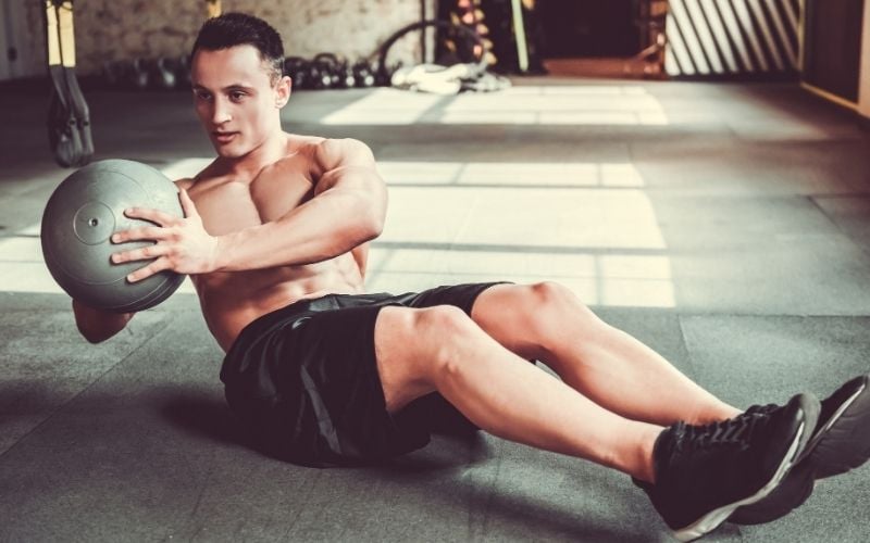Fit man doing russian twists in the gym