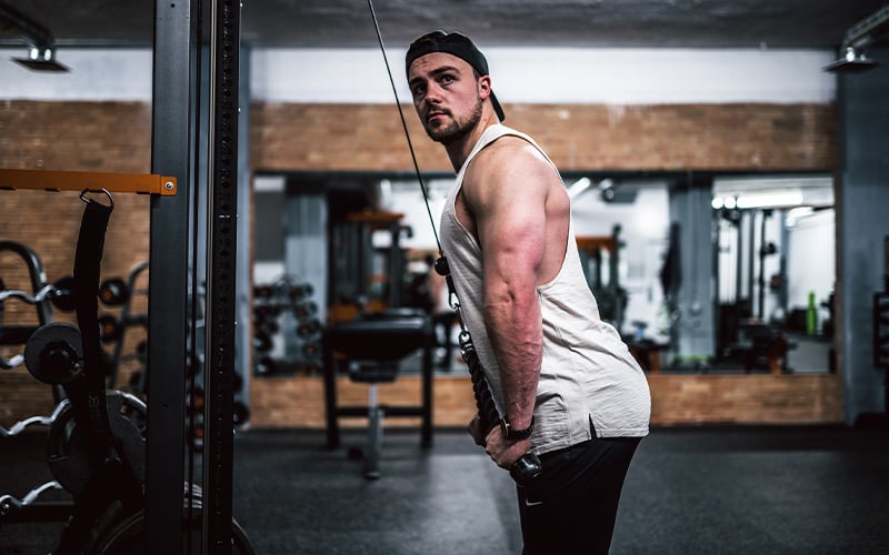 Fit man doing a cable tricep extension in the gym.
