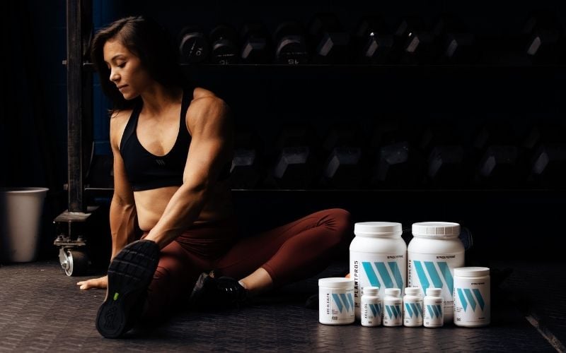 Swolverine athlete stretching next to stack of Swolverine products.