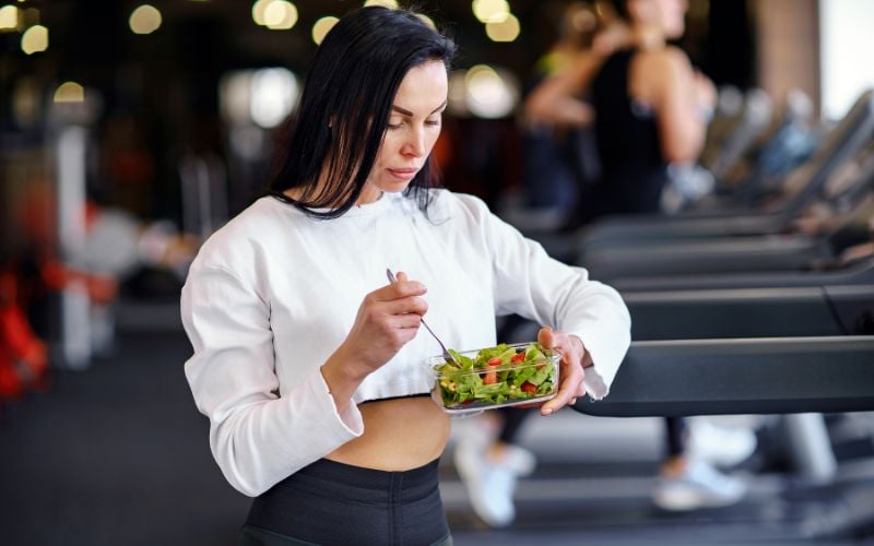 Lean female eating a healthy salad.