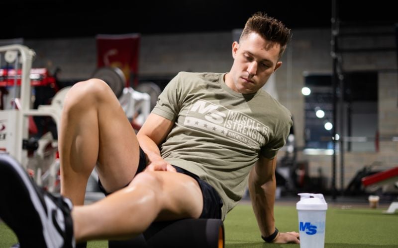 Strong male athlete foam rolling in the gym.