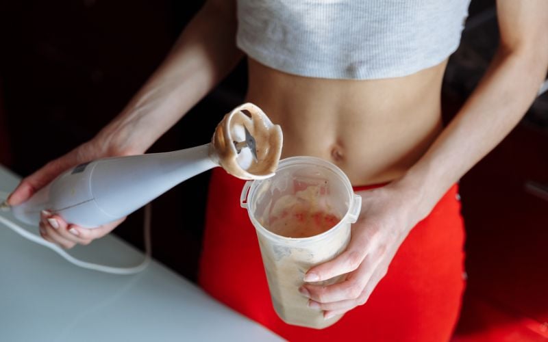 Overhead shot of a lean female making a chocolate protein shake.