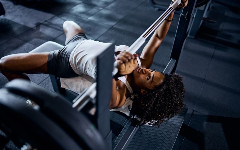 Strong african american woman doing a barbell chest press.