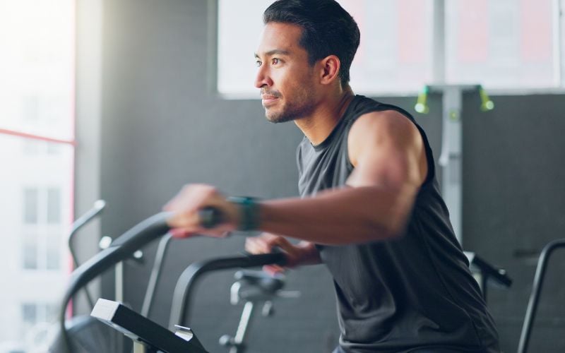 Lean asian man riding a cardio bike in the gym.