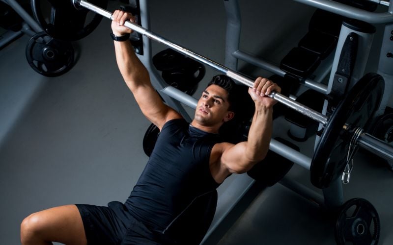 Muscular man doing a barbell bench press in the gym.