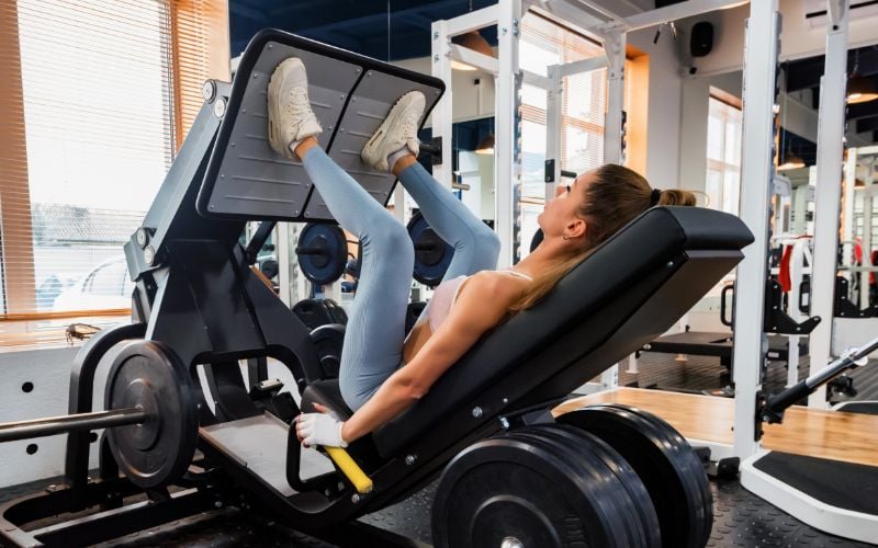 Lean woman doing leg presses in the gym