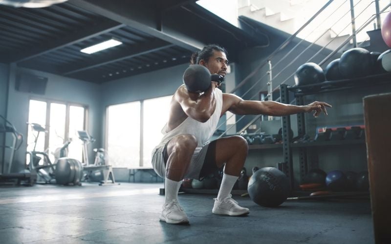 Man doing single arm kettlebell squat.