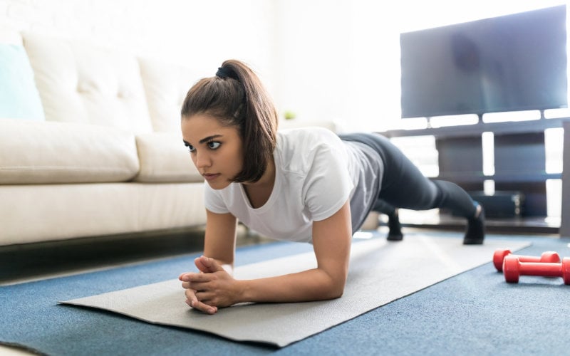 Woman doing plank on floor of living room.