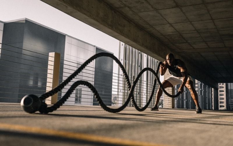 African man in parking garage using battle ropes.