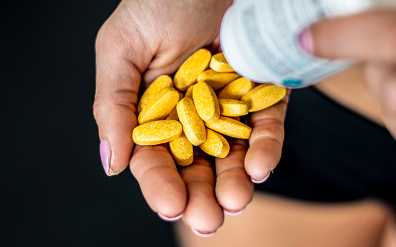 Close up of athlete pouring sports supplements into palms.