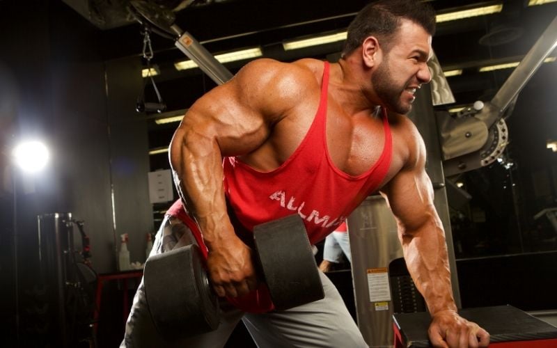 Man in red ALLMAX tank doing single arm dumbbell row.