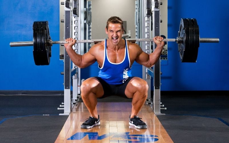 Muscle & Strength Athlete Barbell Squatting in Gym