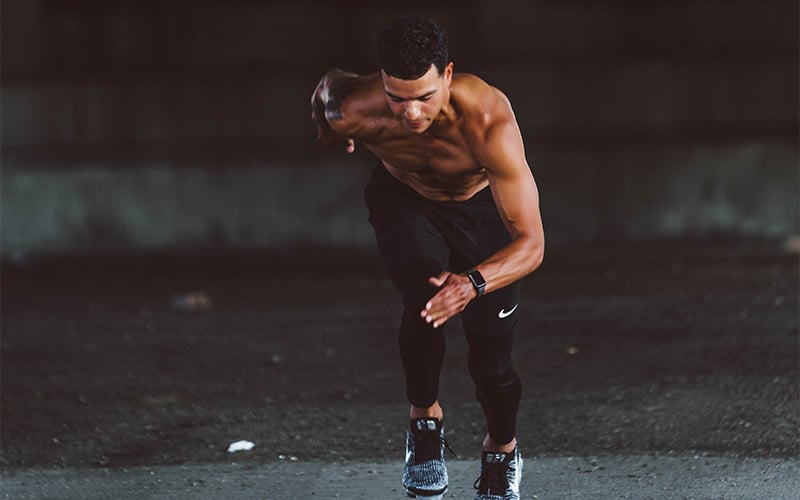 Lean shirtless man running sprints outside