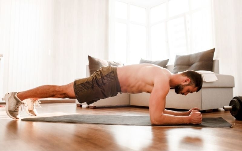 Man doing forearm plank in living room.