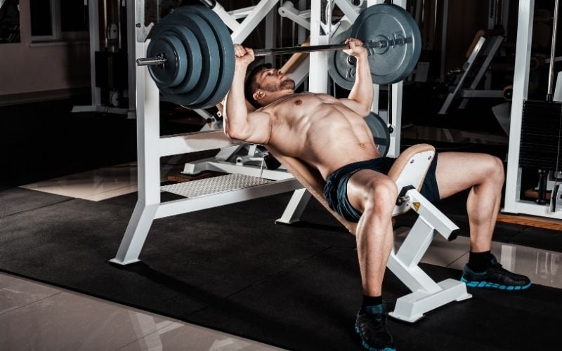 Shirtless male doing incline bench press.