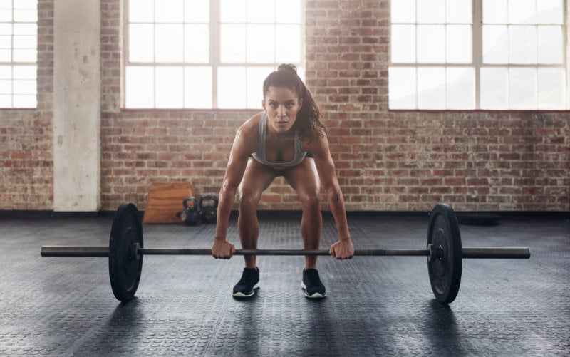 Woman doing deadlifts in CrossFit-style gym.