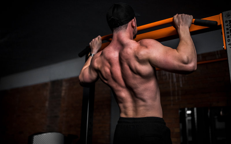 Shirtless man doing pullups.