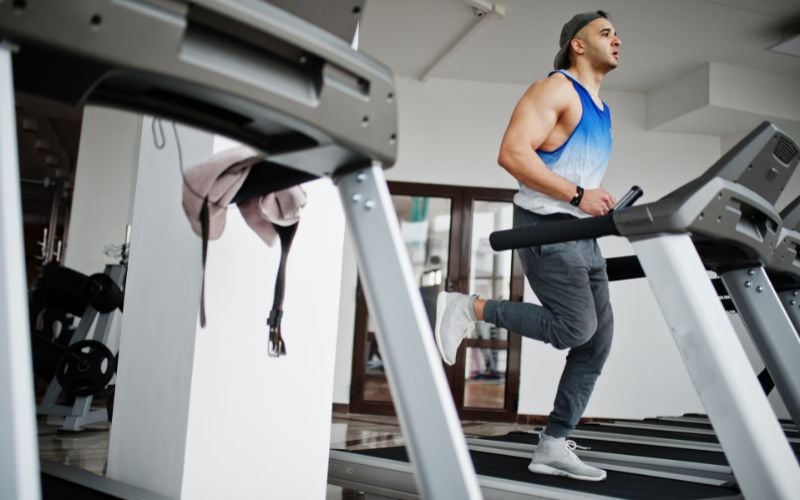 Fit brunette man running on the treadmill at the gym.