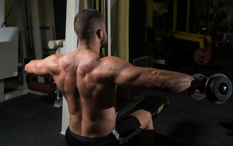 Athletic Man Using Dumbbells for Lateral Raises