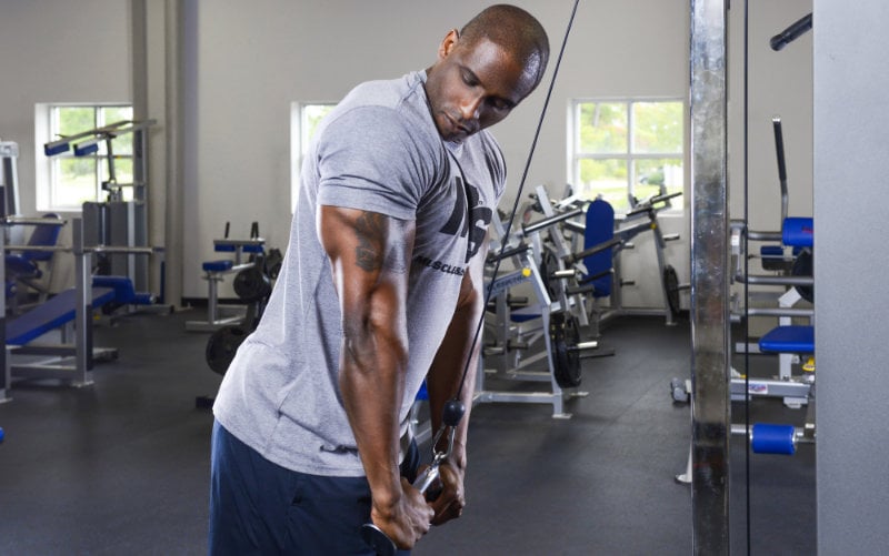 Muscle & Strength model wearing grey M&S t-shirt doing cable tricep pushdowns.