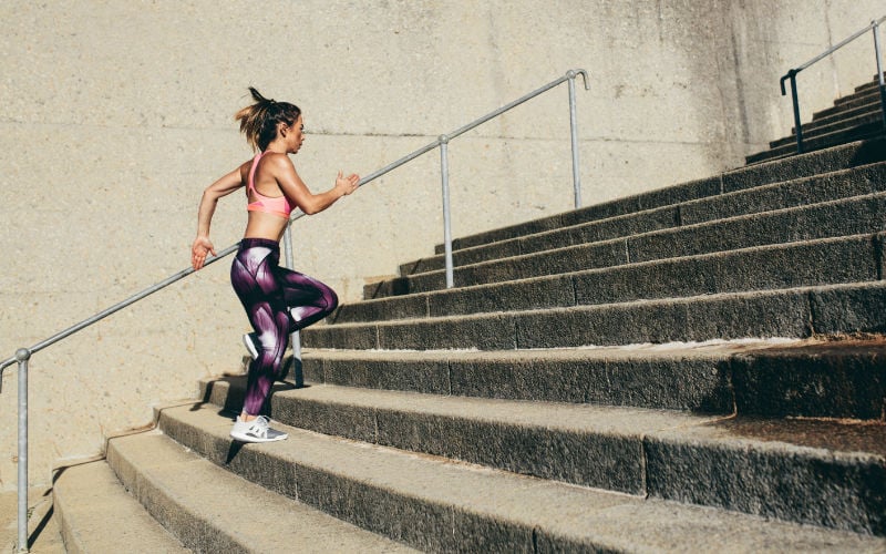 Woman running up stairs outside.