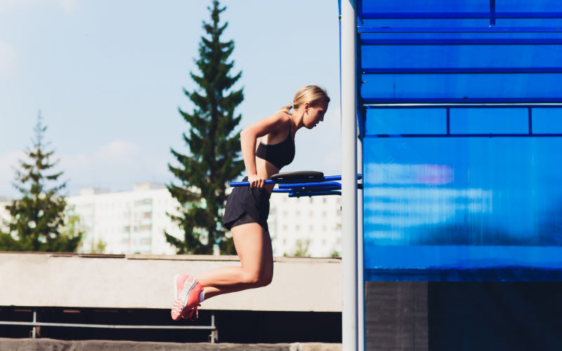 Woman doing tricep dips outside in park. 